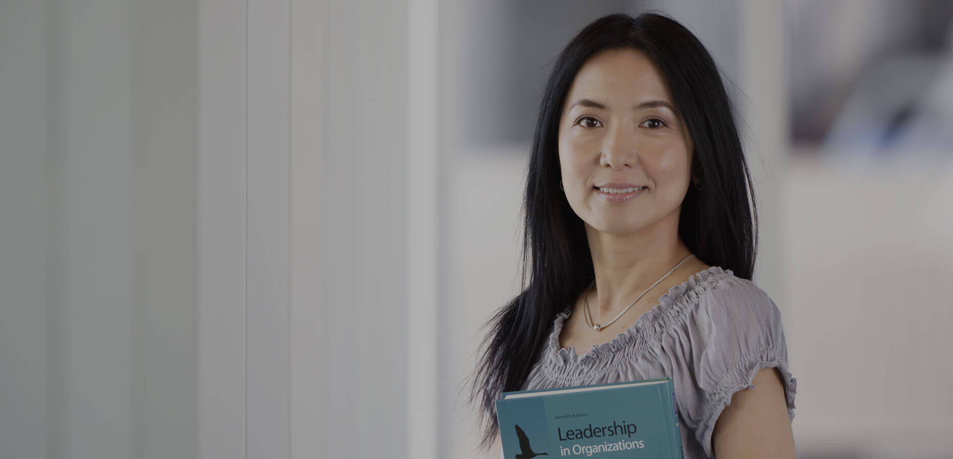 Mature asian learner holding textbook