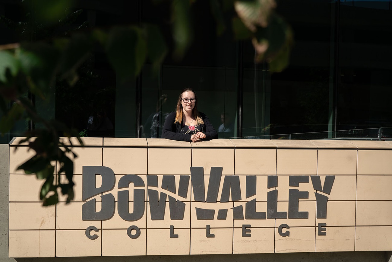 Learner standing in front of Bow Valley College sign