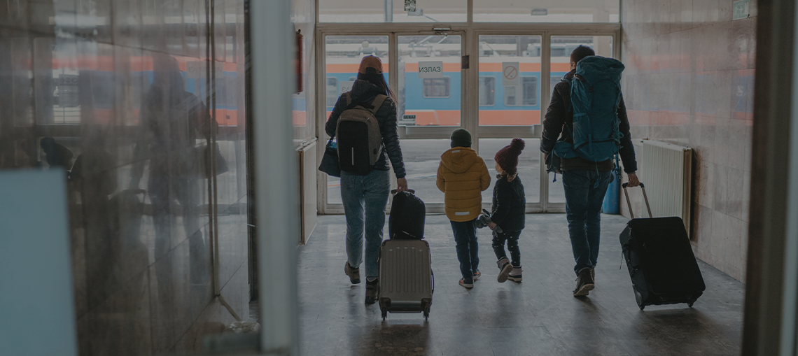 A family with young children carrying luggage in an airport